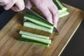 Woman`s Hands Cut Cucumber Matchsticks with Santoku Knife on a Wooden Chopping Board. Salads, Maki and Temaki Sushi Rolls Royalty Free Stock Photo